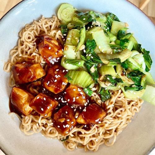 Cubes de saumon nappés de sauce général tao, servir sur un bol de ramen, avec des bok choy poêlés.